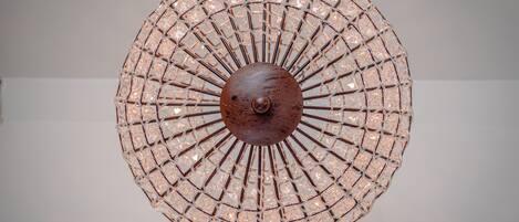 Una lámpara de araña circular con una esfera metálica central y una estructura de entramado de alambre.