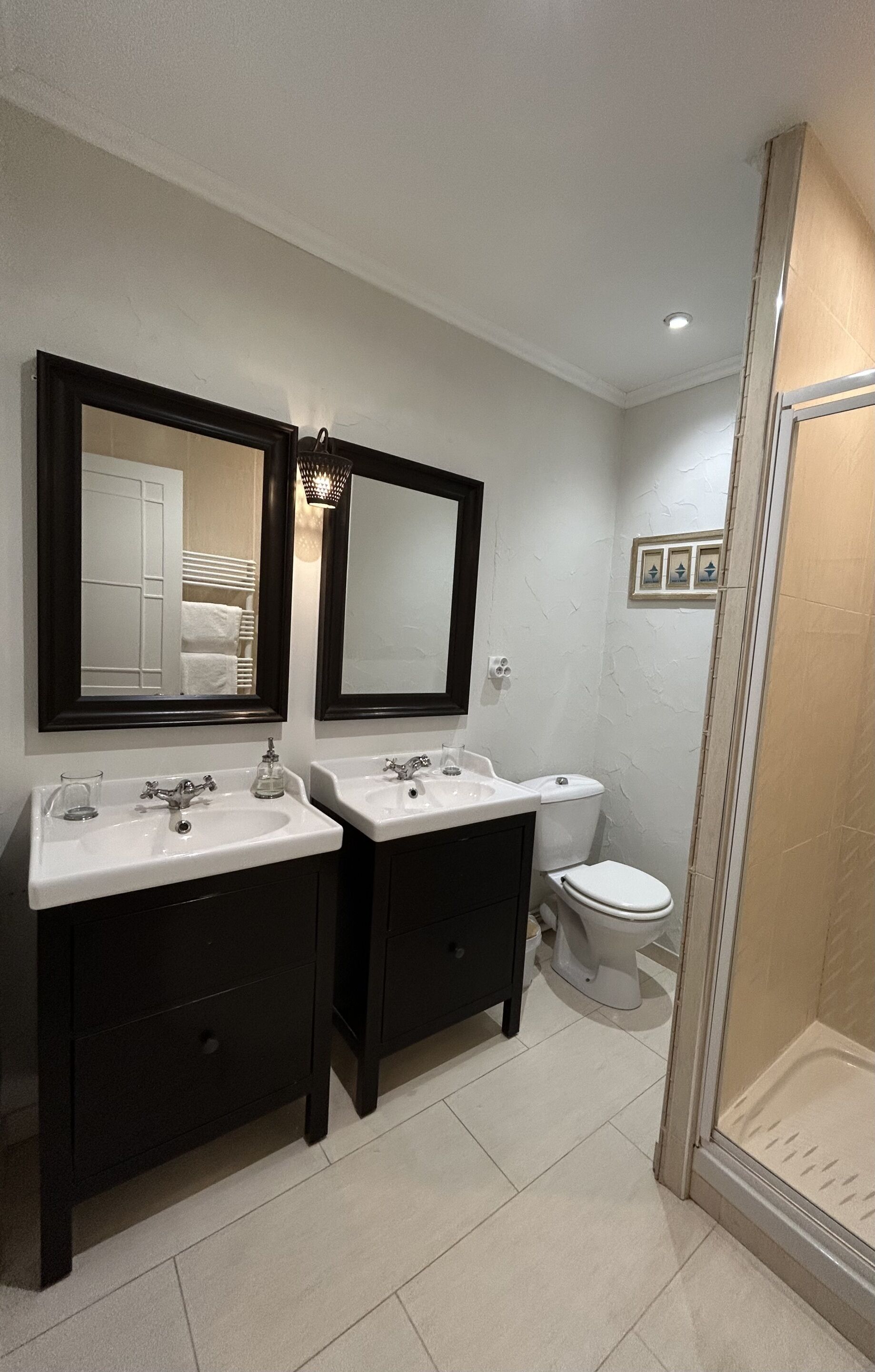 A bathroom with two sinks, a toilet, and a shower.