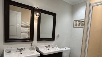 A bathroom with two sinks, a toilet, and a shower.