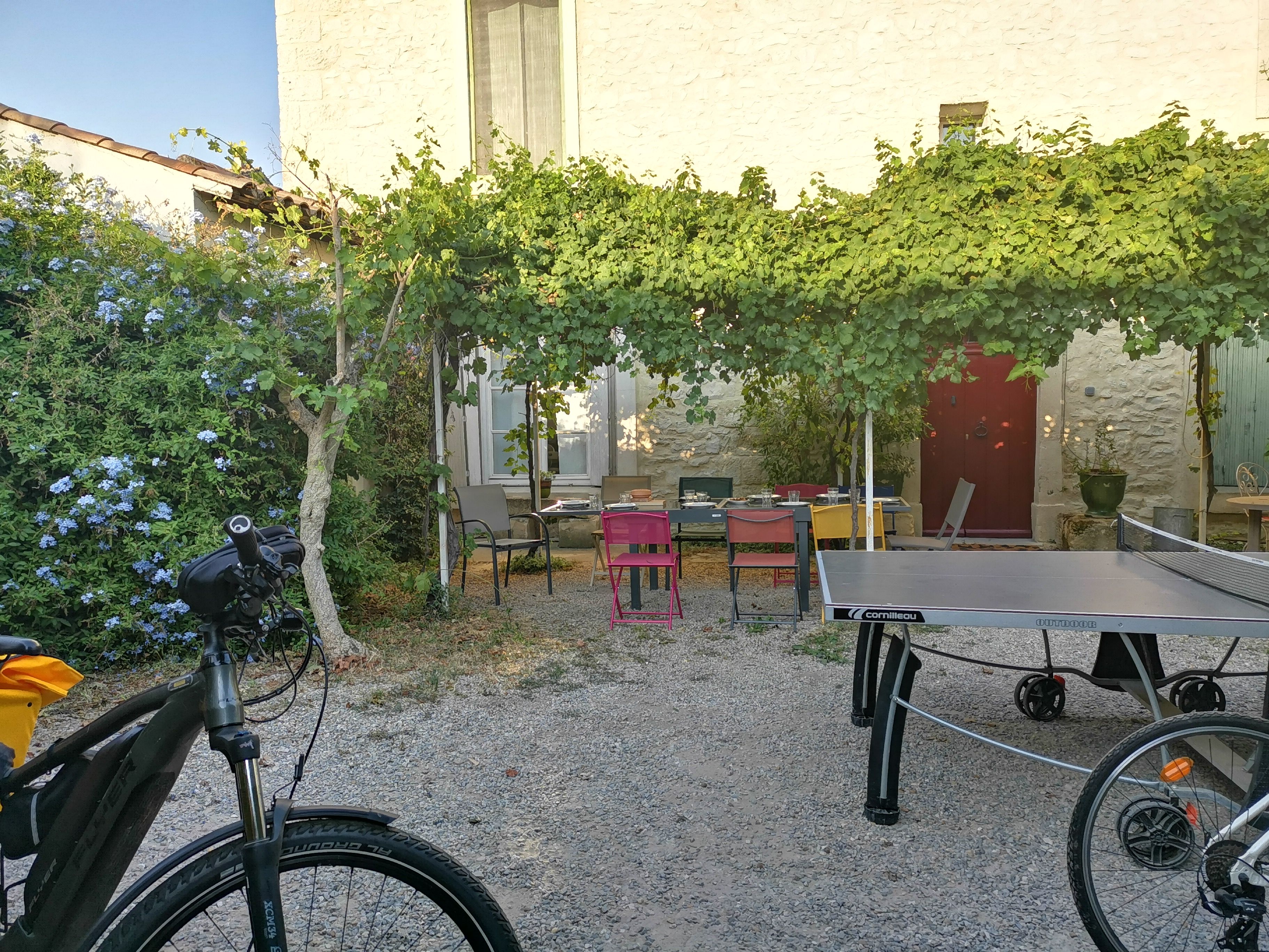 Ein Innenhof mit Tischtennisplatte, Stühlen, einem Fahrrad und einem Gebäude mit einer Steinverkleidung.