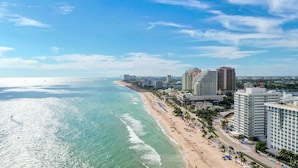 Un paisaje urbano costero con playa, edificios altos y cielo despejado.