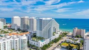A high-rise hotel with multiple floors, a pool on the rooftop, and a view of the ocean.