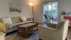 A living room with a sofa, armchair, coffee table, and a painting on the wall. - Flip Flop 1 (Sanibel)