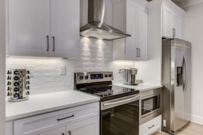 A modern kitchen with white cabinets, stainless steel appliances, and a built-in oven.