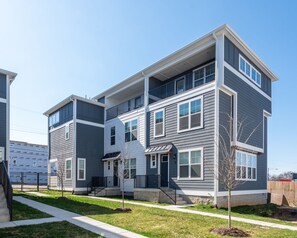 A multi-story residential building with a modern design, featuring a flat roof, large windows, and a covered front porch.