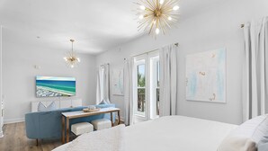 Ein modernes Hotelzimmer mit einem großen Bett, einem Schreibtisch mit Stuhl, einer Couch und Kunstwerken an den Wänden.