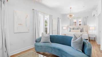 A modern bedroom with a blue sofa, a large bed, and a chandelier.
