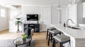 Eine moderne Küche mit weißer Arbeitsplatte, Barhocker und integriertem Spülbecken.