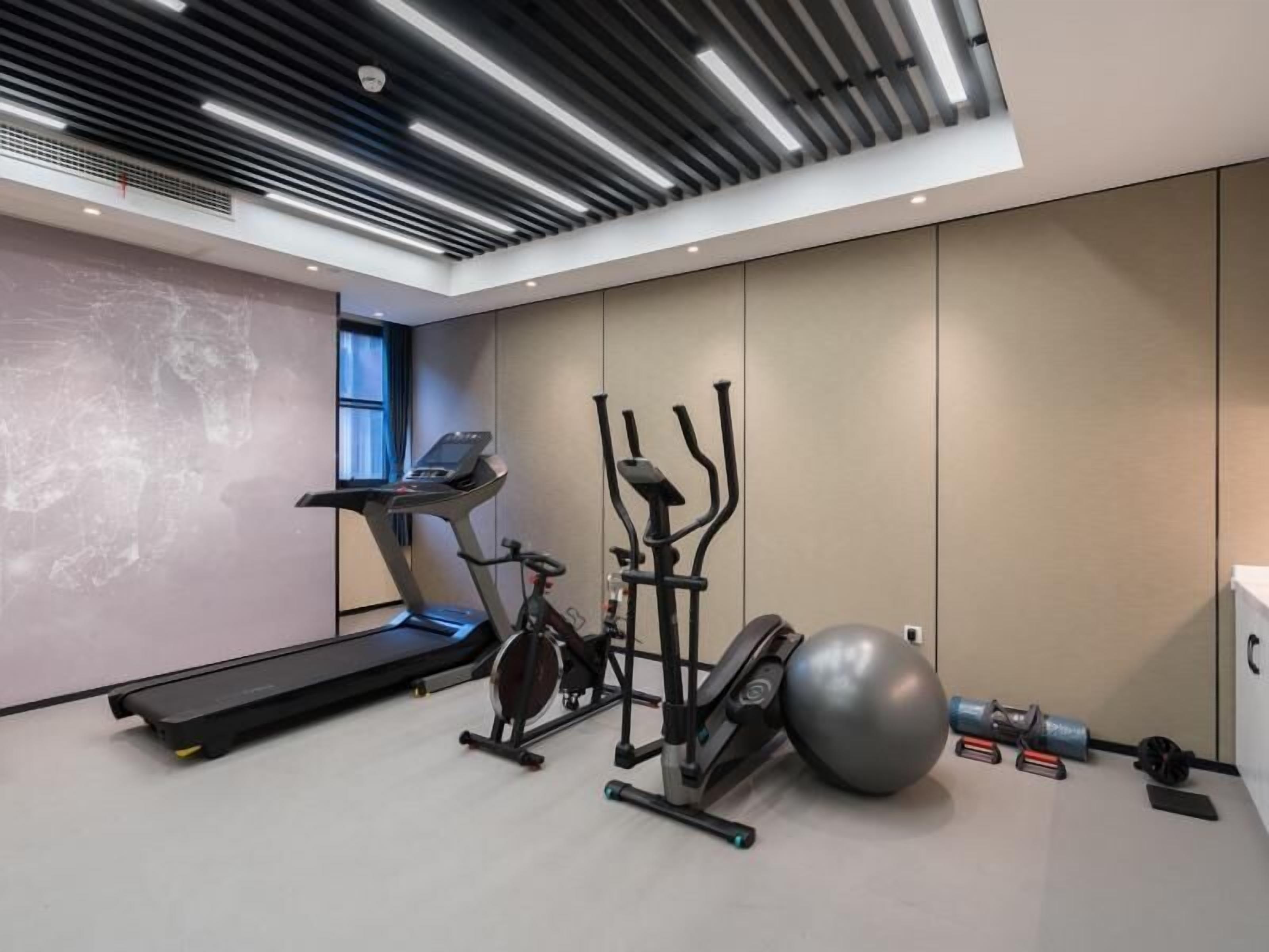 A modern gym with a treadmill, elliptical, stationary bike, and exercise ball.