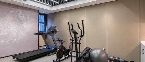 A modern gym with a treadmill, elliptical, stationary bike, and exercise ball.