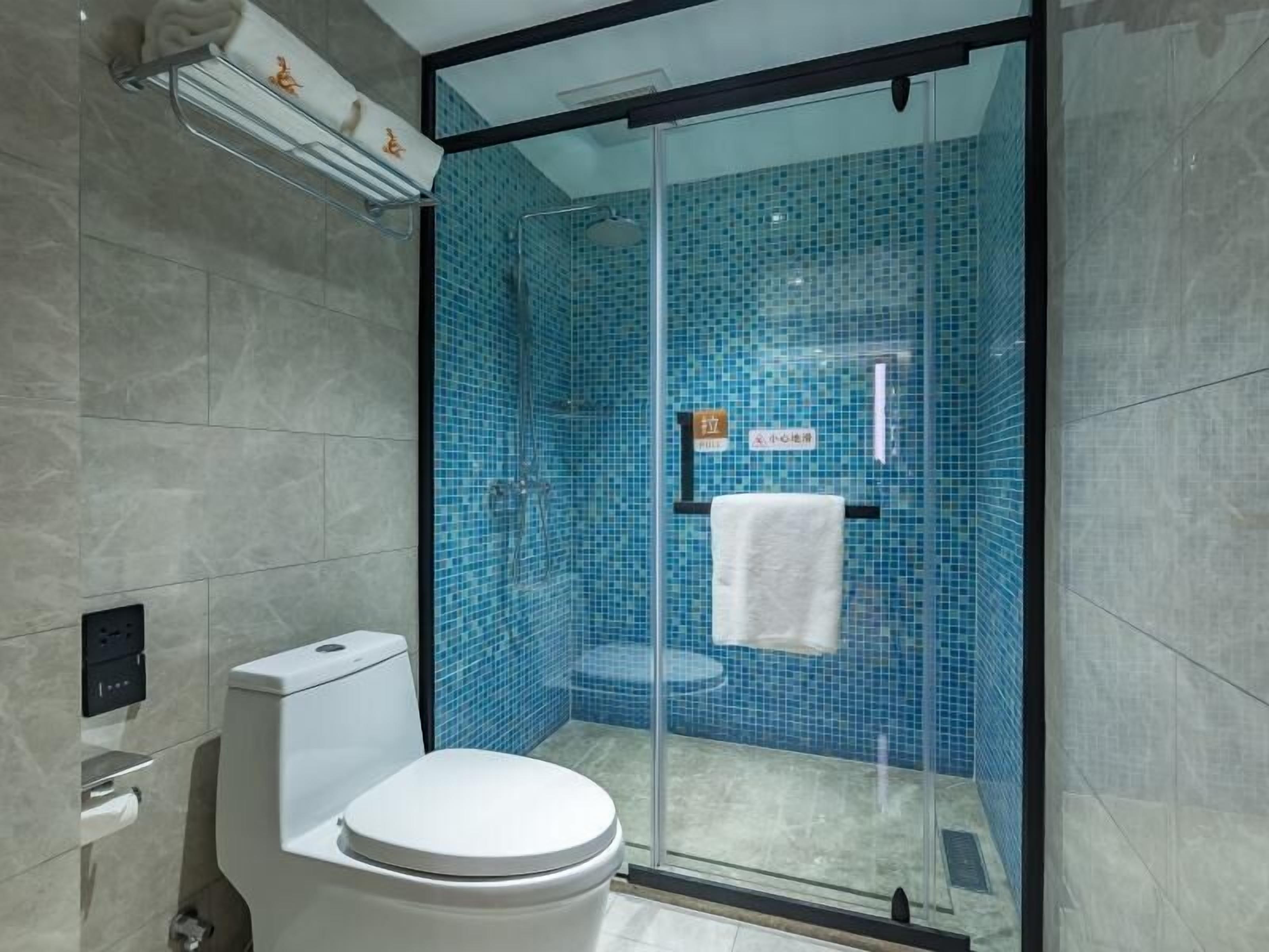 A modern bathroom with a glass-enclosed shower, a toilet, and a towel rack.