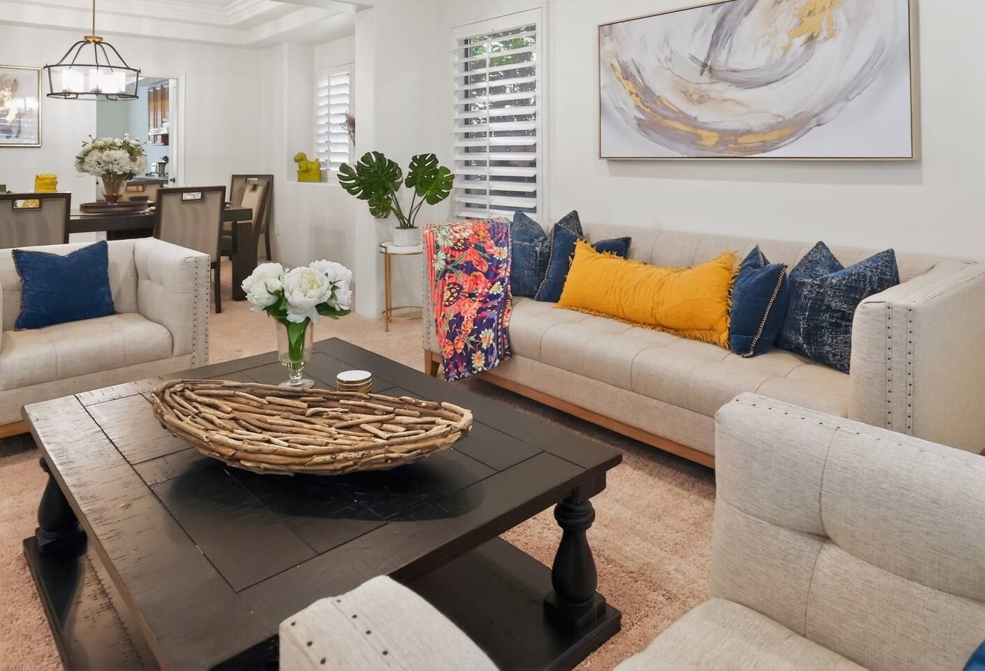 A living room with a sofa set, a coffee table, and a decorative vase with flowers.