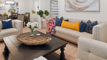 A living room with a sofa set, a coffee table, and a decorative vase with flowers.