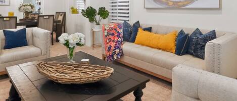 Una sala de estar con un sofá, una mesa de centro y un jarrón decorativo con flores.