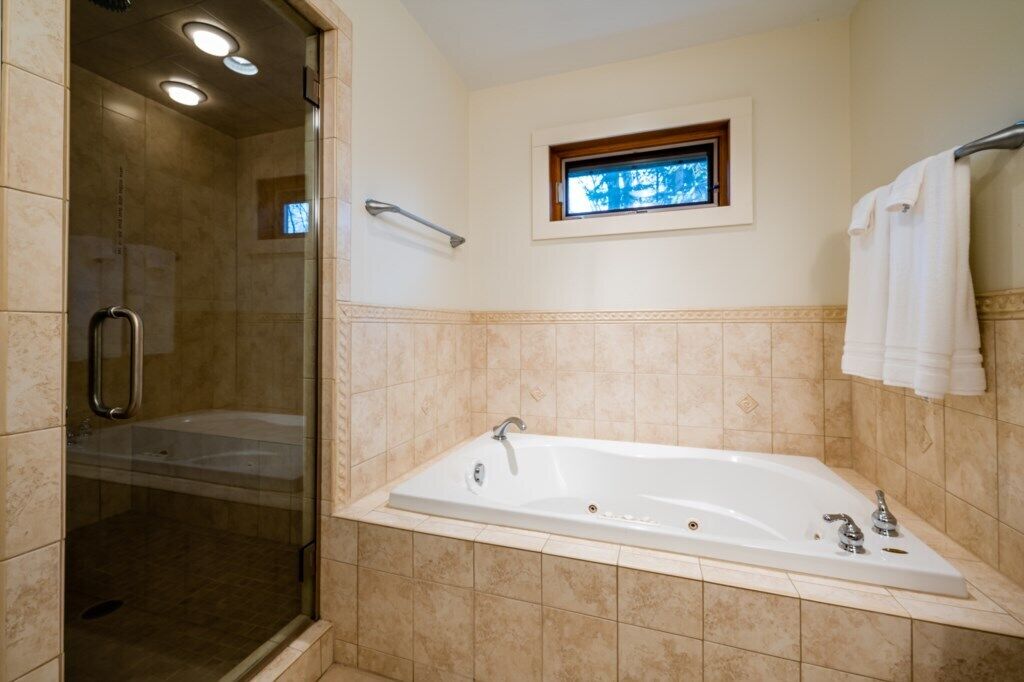 Une salle de bain avec une douche à l’italienne, une baignoire et une petite fenêtre.