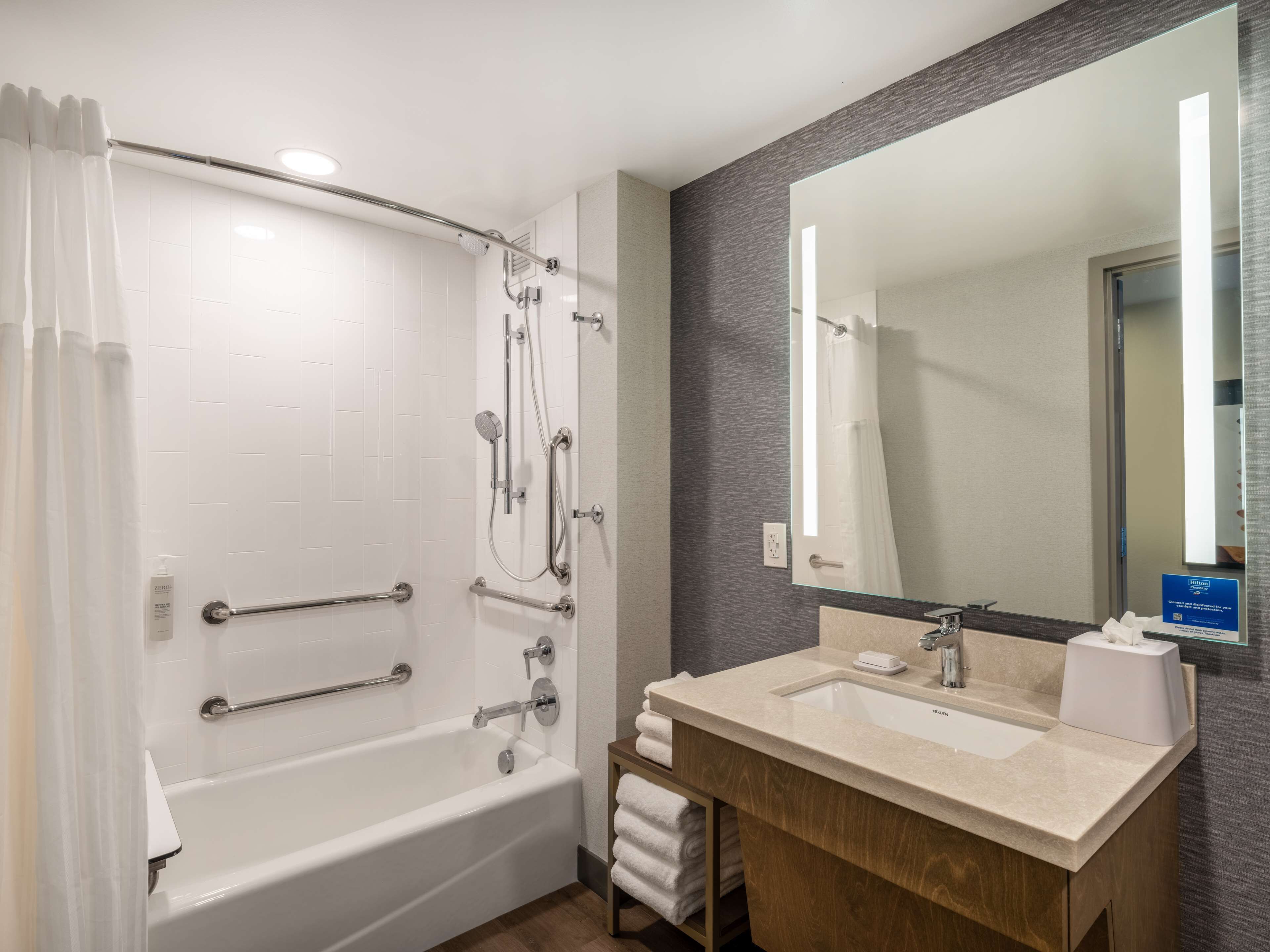 A modern bathroom with a bathtub, shower, and vanity with a sink and mirror.