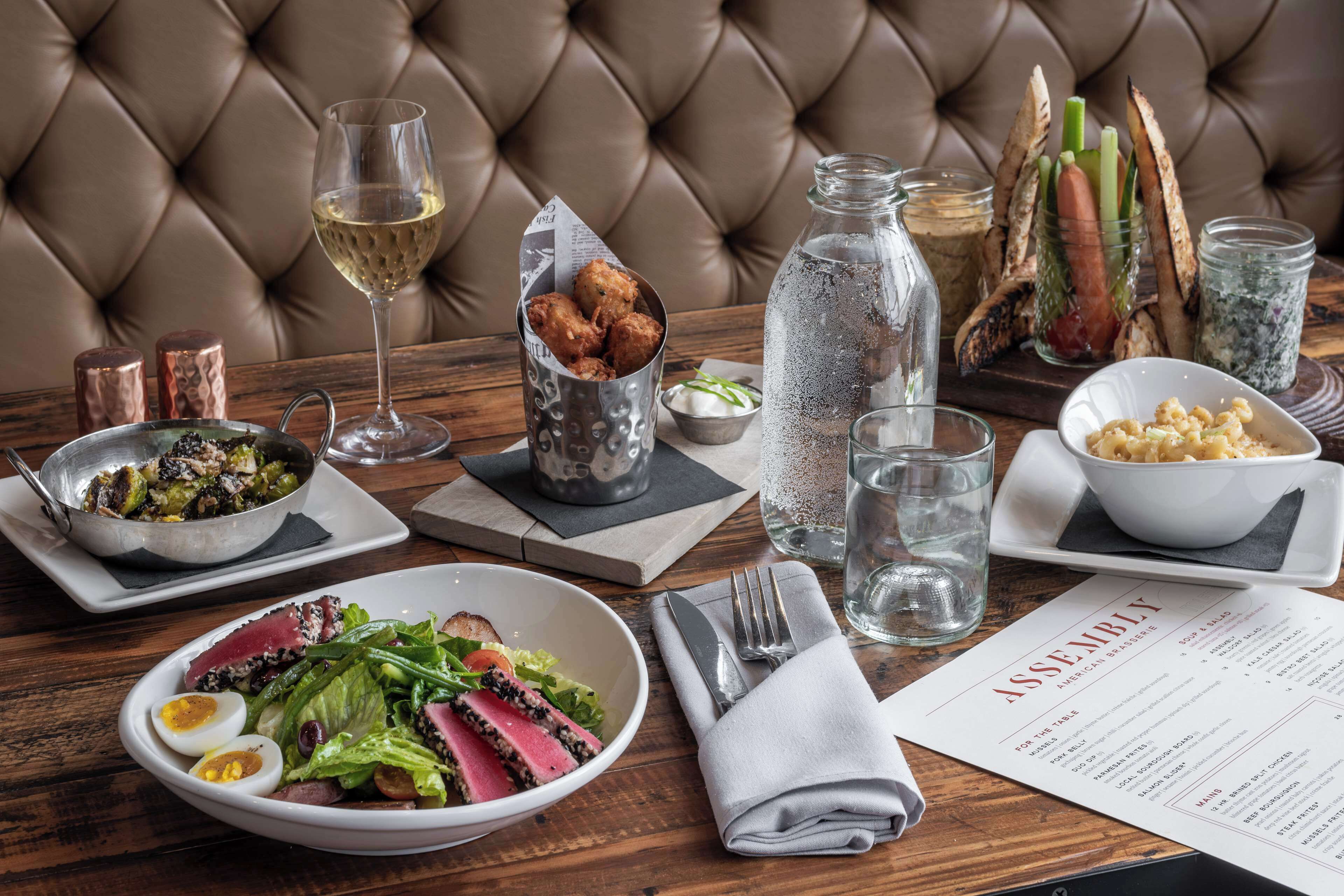 A dining table with various dishes, a menu, and a bottle of water.