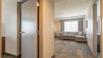 Ein Hotelzimmer mit einer großen Couch, einem kleinen Tisch und Blick auf die Stadt durch das Fenster.