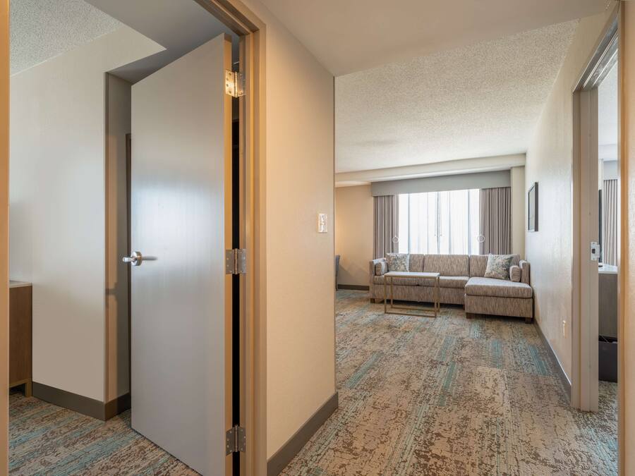 Ein Hotelzimmer mit einer großen Couch, einem kleinen Tisch und Blick auf die Stadt durch das Fenster.