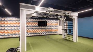 Un gimnasio con piso verde, una pared de diseño geométrico y una puerta negra.