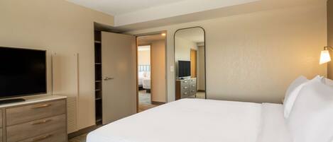 Una habitación de hotel con una cama, un televisor en una cómoda, un espejo y una cómoda con cajones.