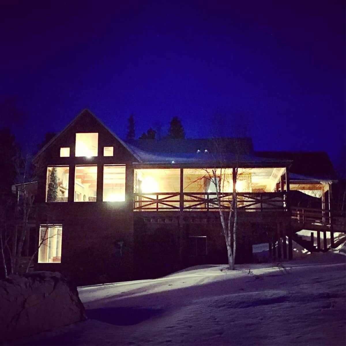 A wooden cabin with large windows and a covered porch.