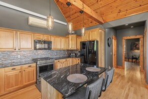 A modern kitchen with wooden cabinets, a black granite countertop, and a stainless steel refrigerator.