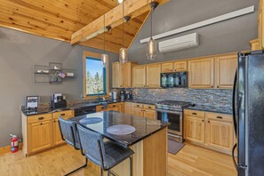 A modern kitchen with wooden cabinets, a black refrigerator, and a large island with chairs. - Your Perfect Black Hills Adventure Starts at The Lodge on High Ridge Trail! (Lead)