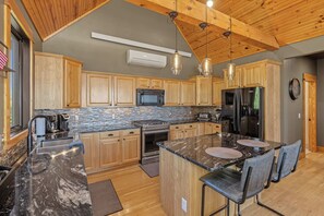A kitchen with wooden cabinets, a granite countertop, stainless steel appliances, and pendant lighting. - Your Perfect Black Hills Adventure Starts at The Lodge on High Ridge Trail! (Lead)