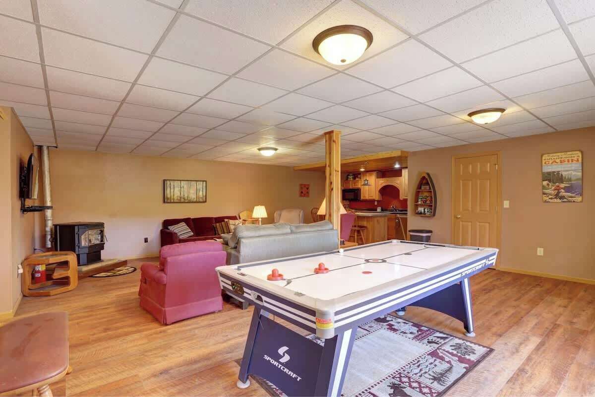 A cozy living room with a foosball table, a sofa, a fireplace, and a kitchen area in the background.