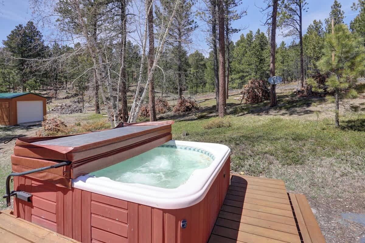 A hot tub on a wooden deck surrounded by a forested area.