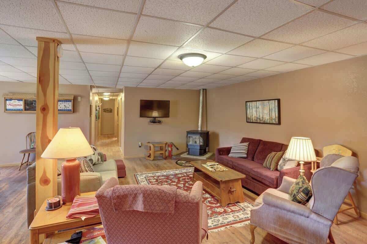 A cozy living room with a sofa, armchairs, a coffee table, a lamp, a TV, and a fireplace.