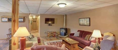 A cozy living room with a sofa, armchairs, a coffee table, a lamp, a TV, and a fireplace.