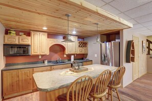 Kitchen area with a central island, stainless steel appliances, and wooden ceiling with exposed beams.