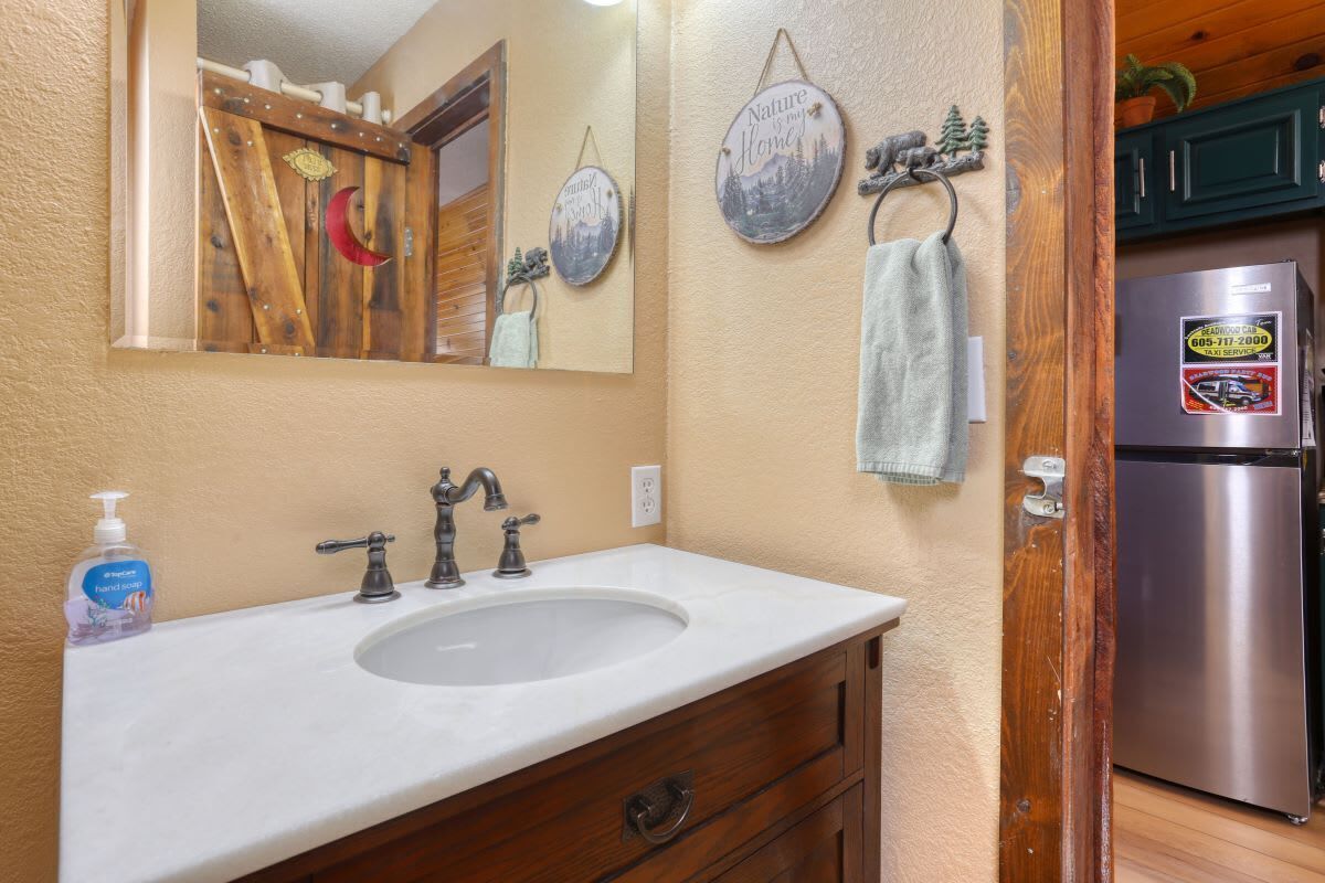 A bathroom with a wooden vanity, a sink, and a mirror. There are decorative plates on the wall and a towel hanging on a rack.