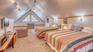 Een gezellige slaapkamer op zolder met twee bedden, een bureau, een televisie en een plafondventilator.