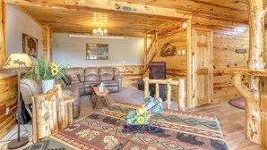 L’intérieur chaleureux d’un chalet en bois comprend un canapé, un tapis à motifs et une table en bois originale.