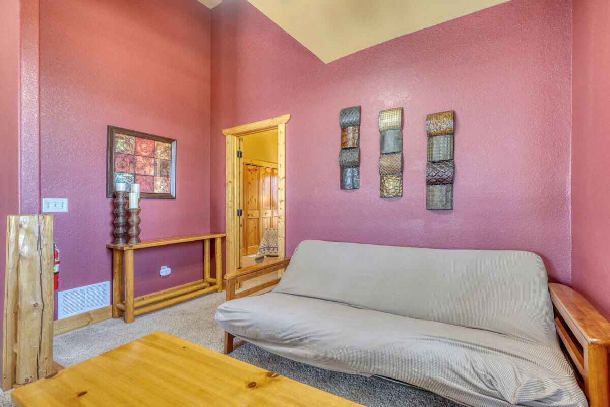A room with a red wall, a wooden bench, a gray sofa, and a wooden door.