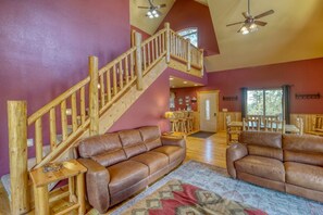 A spacious living area with a wooden staircase, leather sofas, and a dining area with wooden furniture. - Rustic Luxury Awaits at Red Antelope Lodge (Lead)