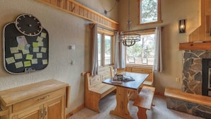 Interior acogedor de una cabaña con chimenea de piedra, muebles de madera y un tablón de anuncios con notas.