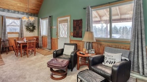 A cozy room with a wooden ceiling, a dining area with a table and chairs, a leather sofa, and a window with curtains. - Cozy Black Hills Retreat – Loft, deck, pet-friendly & peaceful mountain views! (Lead)