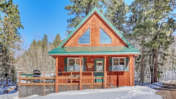 A wooden cabin with a green roof, a front porch, and a sign that reads "Stuck's". - Cozy Black Hills Retreat – Loft, deck, pet-friendly & peaceful mountain views! (Lead)