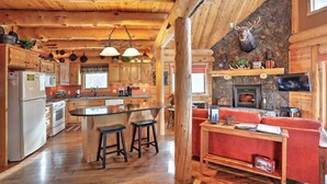 A rustic cabin interior with a kitchen, dining area, and living room. - Wannabee Moose Lodge (Sturgis)