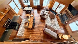 Un salón amplio con piso de madera, un conjunto de sofás, una mesa de comedor y una cocina con estufa y alacenas.
