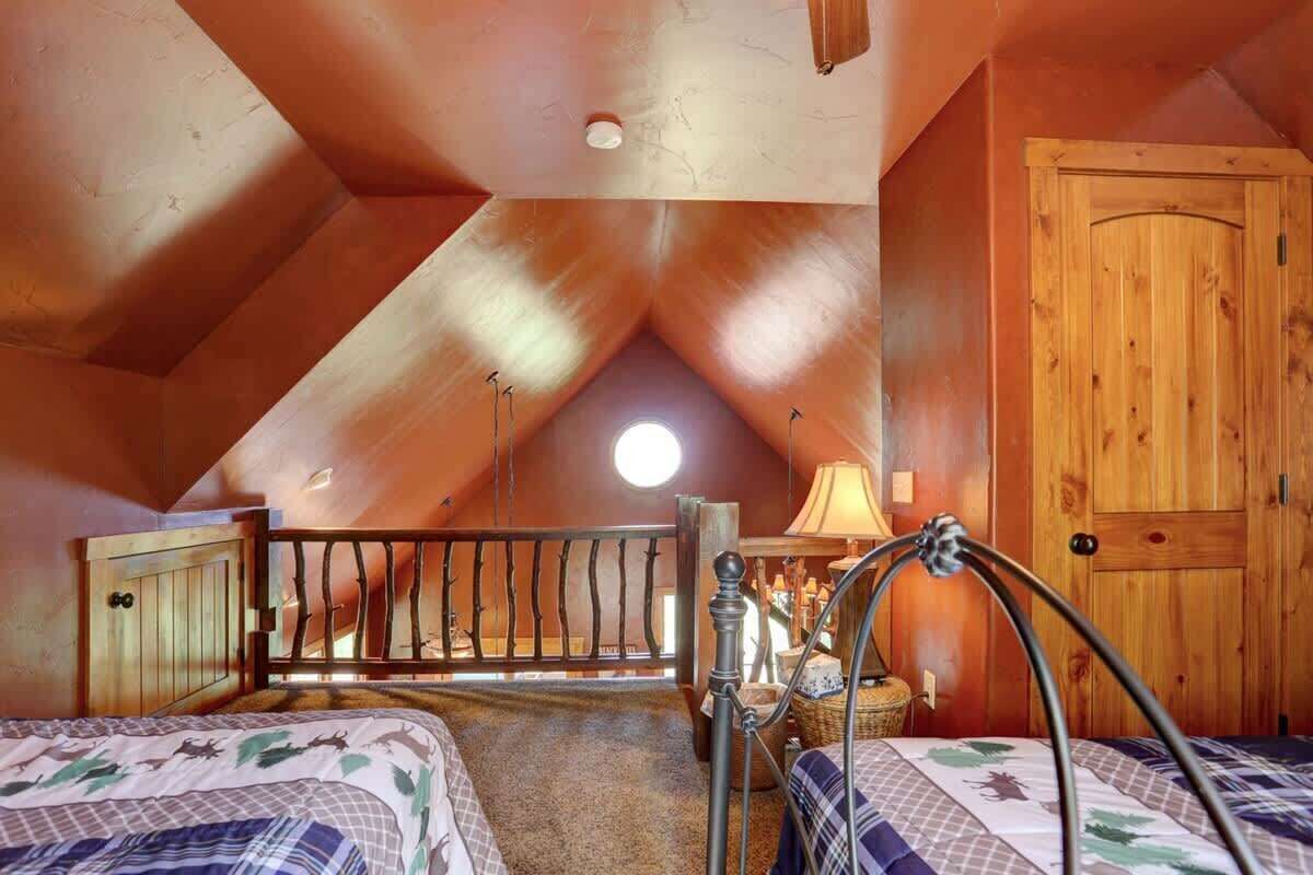 A cozy attic bedroom with a sloped ceiling, a wooden door, and a bed with a patterned bedspread.