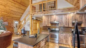 A spacious kitchen with wooden cabinets, a central island, and a staircase leading to an upper level.
