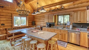 A log cabin with a large kitchen, wooden bar stools, and a chandelier. - Deer Haven Lodge – Spacious Family Cabin with Hot Tub, Game Room & Scenic Views (Lead)