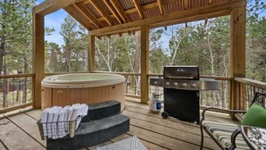 Une terrasse extérieure couverte avec un jacuzzi, un barbecue et un espace salon extérieur.