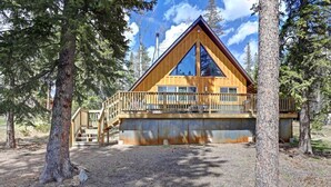 A cabin with a wooden exterior, a balcony, and a gravel ground.