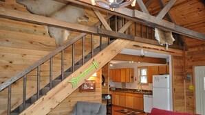 A wooden interior with a staircase, a kitchen, and a living area.